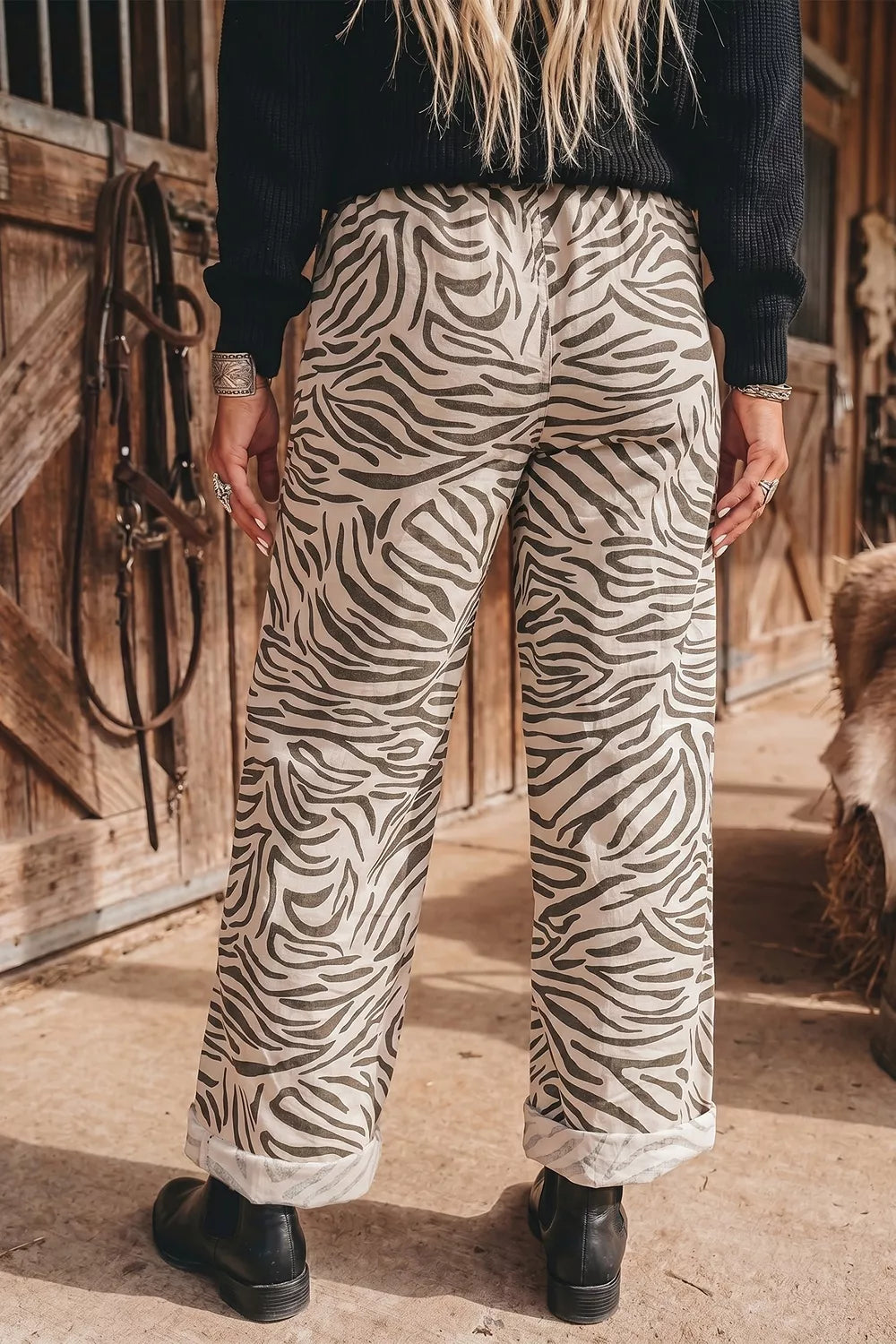 Back view of the zebra print wide leg pants worn with black boots