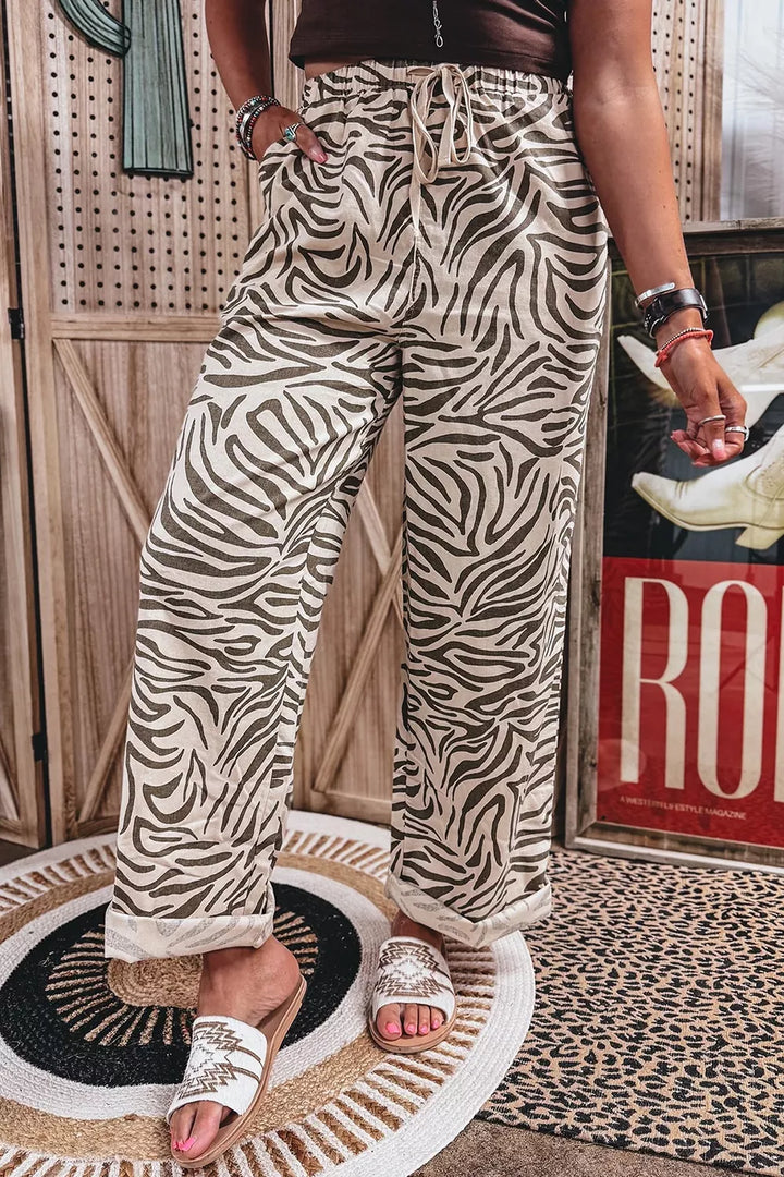 Full-length zebra print wide leg pants with white slide sandals and a rug
