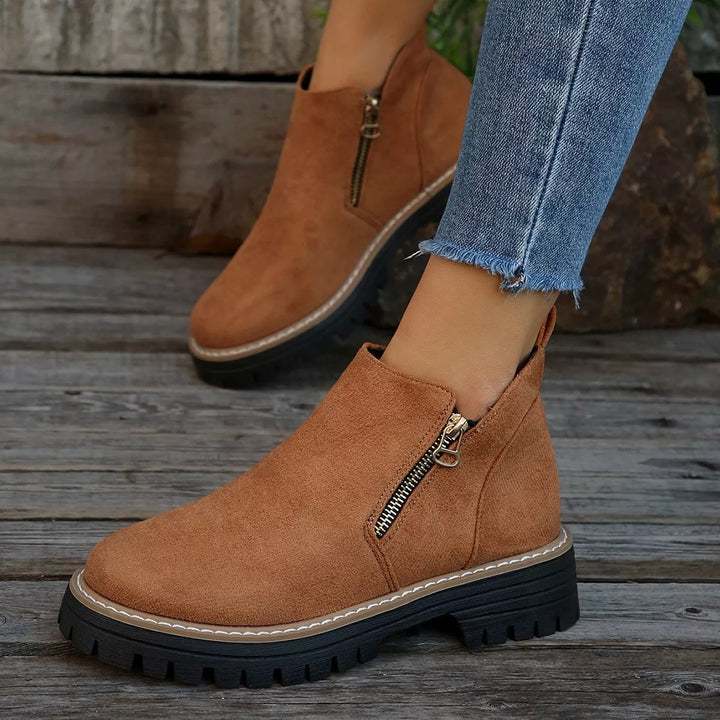 Camel ankle boots with a chunky lug sole and zipper, close view on feet