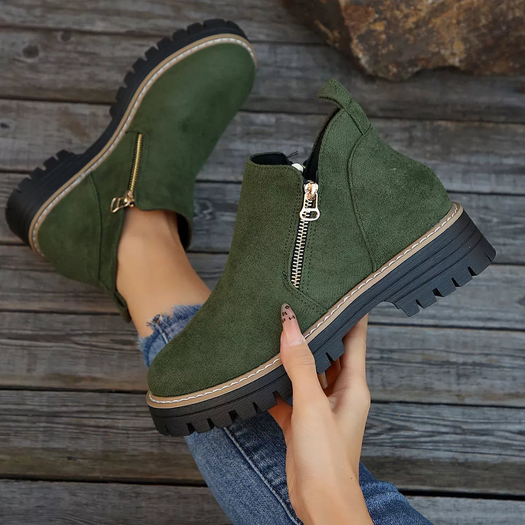 Olive green zipper boot held in hand to show the lug sole profile