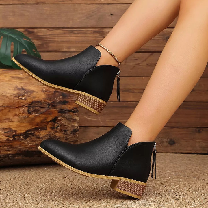 Black V-cut ankle boots with a back zip tassel, angled side view