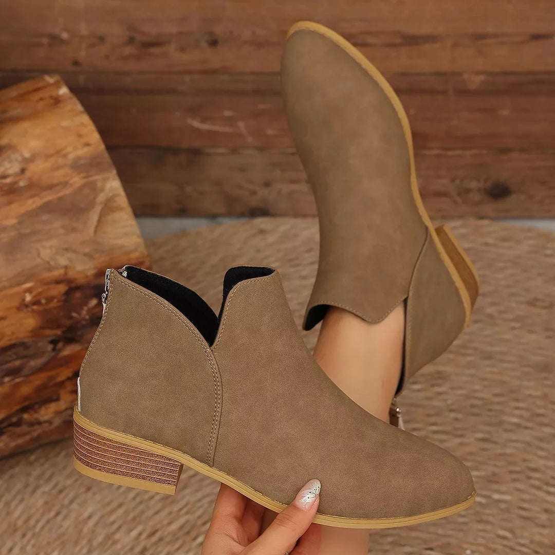 Brown V-cut ankle boot held in hand to show the heel and side profile