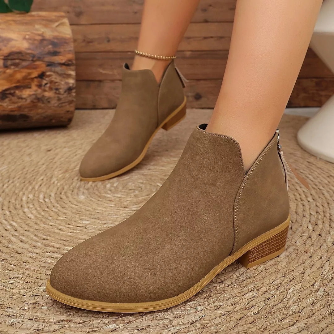 Brown ankle boots with a V-cut front and low block heel, worn on a rug