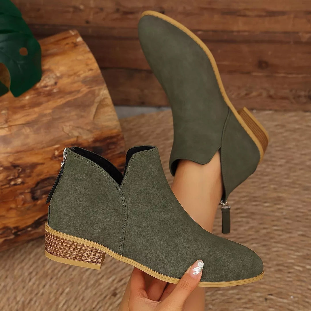 Olive ankle boot held in hand to show the V-cut and heel
