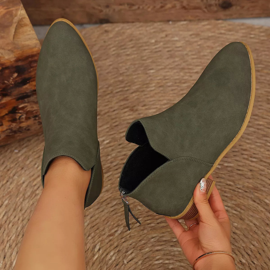 Pair of olive block heel ankle boots seen from above, one held by hand