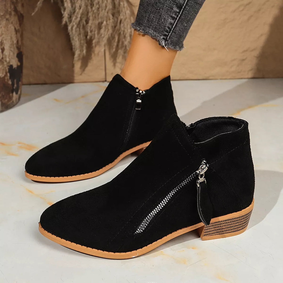 Black pointed toe ankle boots with side zip, worn with cuffed gray jeans