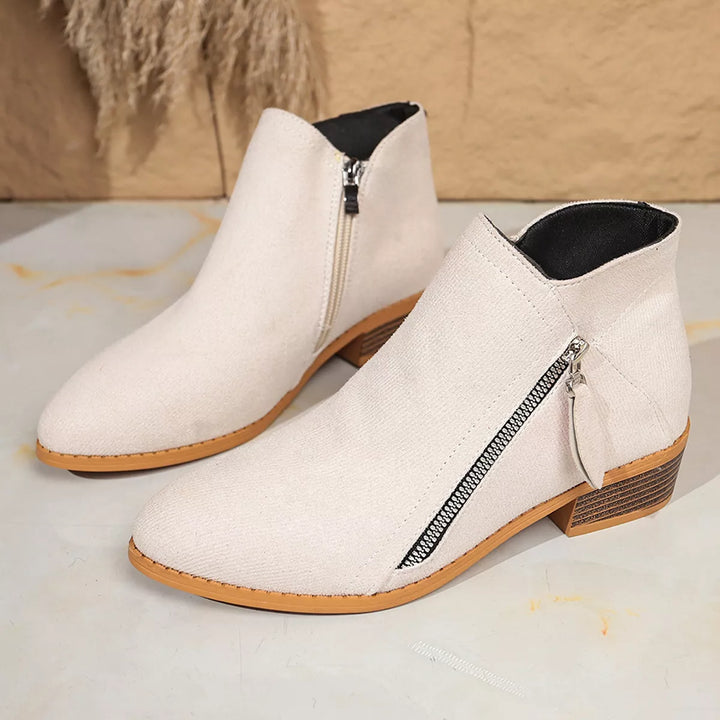 Pair of cream pointed toe ankle boots showing the zipper side