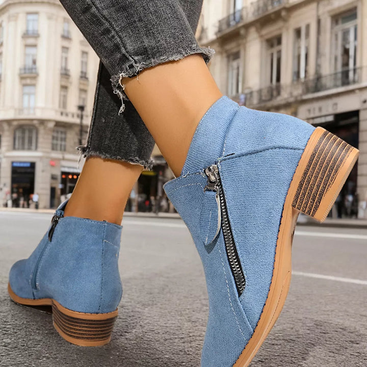 Light blue ankle boots with side zip and block heel, worn on a city street