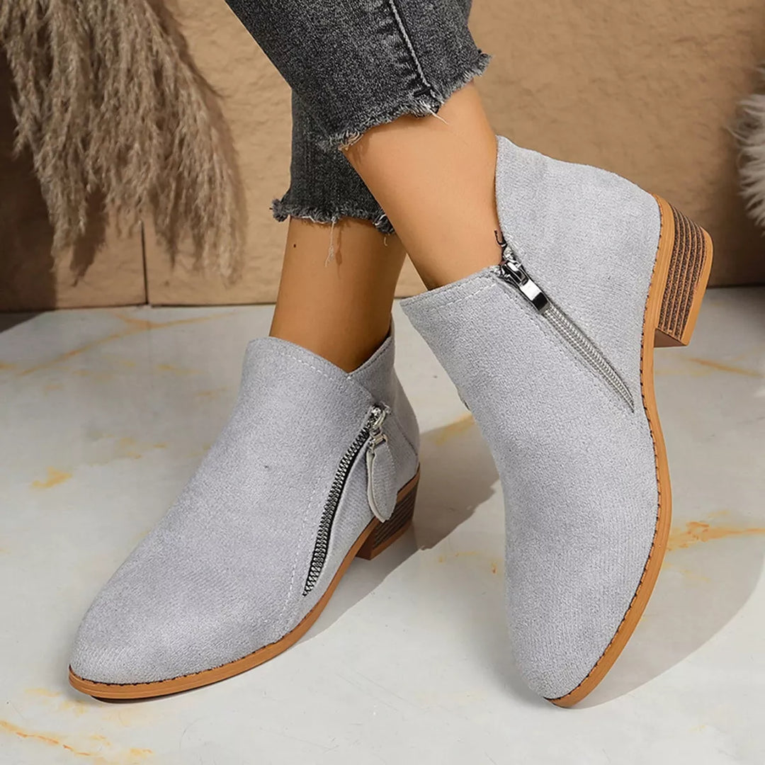 Light gray ankle boots with side zip and block heel, worn with jeans