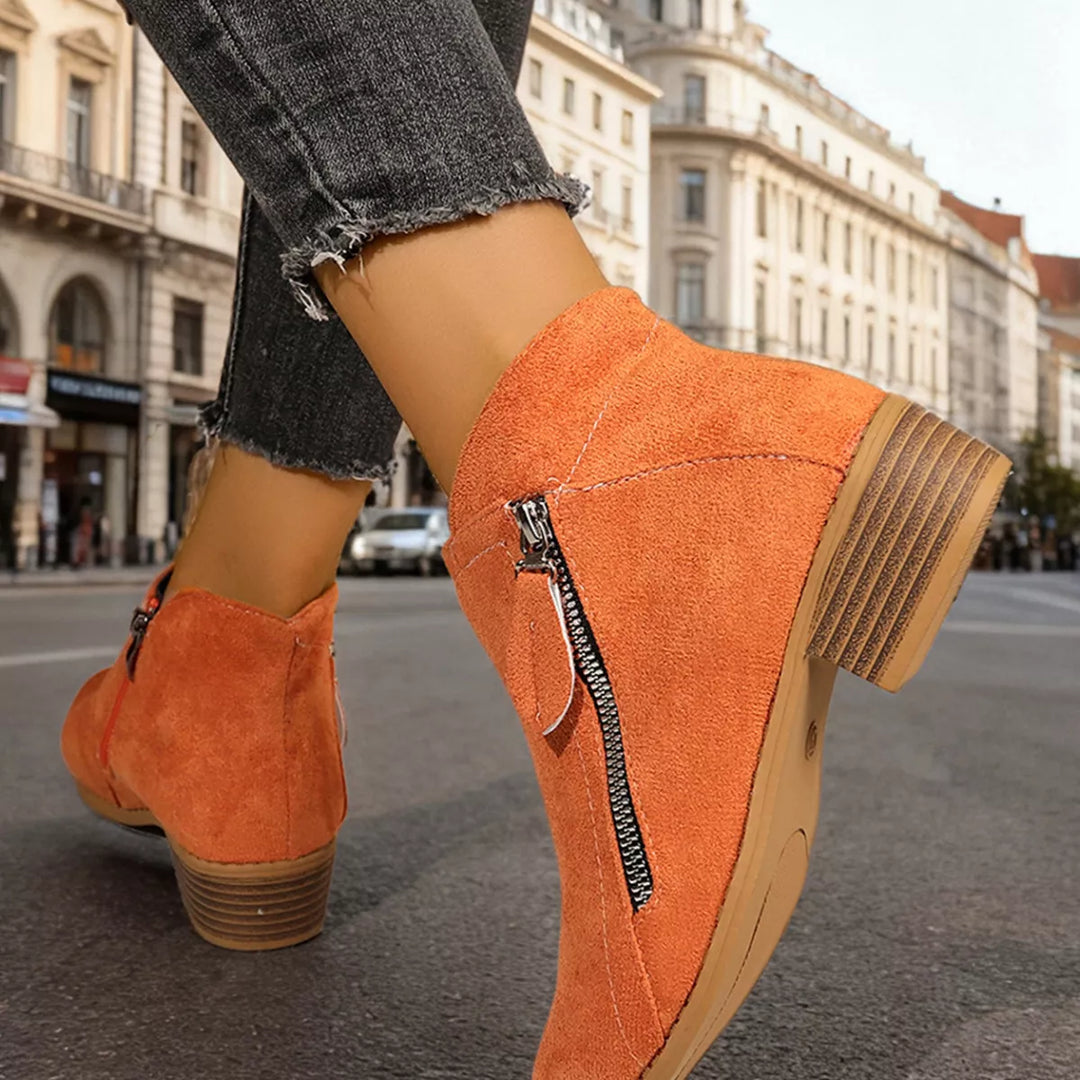 Orange block heel ankle boots in a walking pose on a street