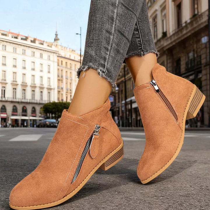 Tan ankle boots with block heel and side zip, worn with cuffed jeans on a street