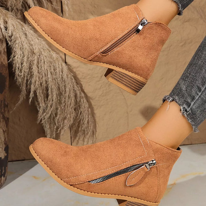 Tan pointed toe ankle boots seen from the zipper side
