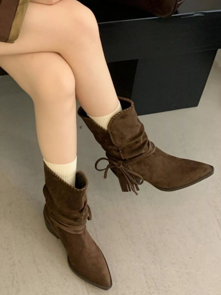 Dark brown ankle boots with fringe tie worn with legs crossed