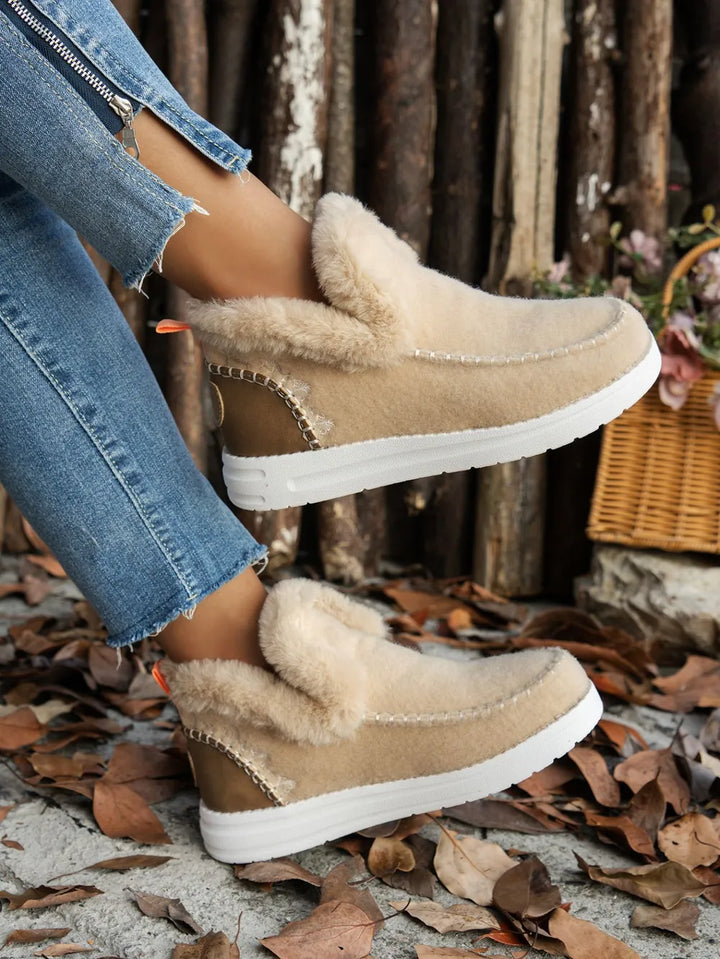 Beige ankle boot with fur-look cuff and white sole, side view on foot