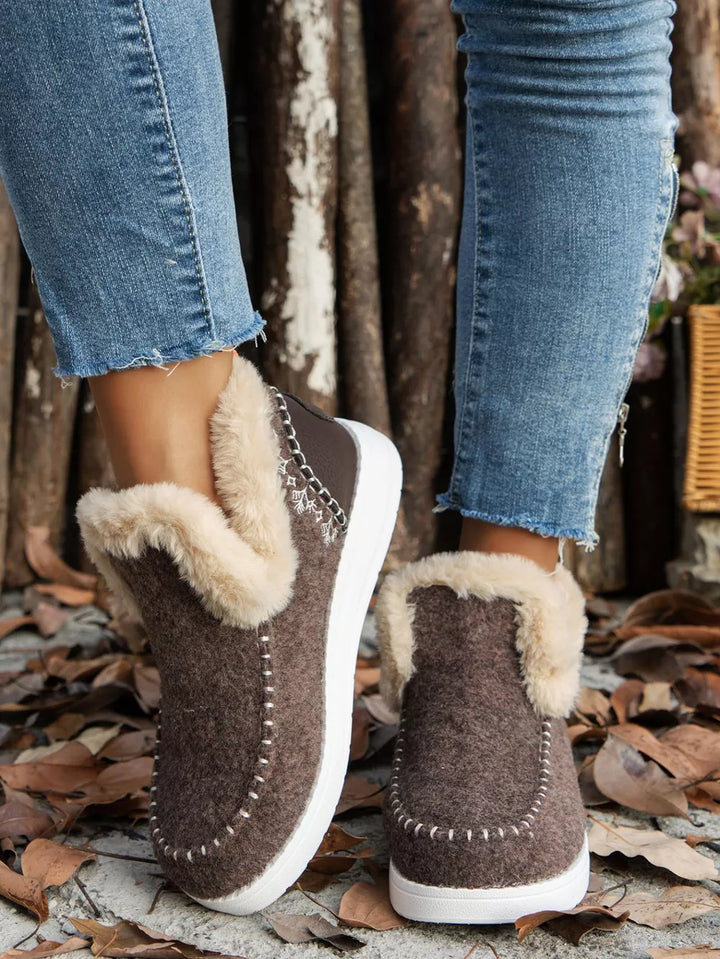 Brown slip on ankle boots with a fur-look cuff and white sole, front view