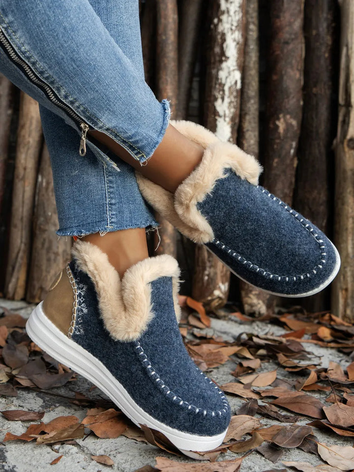 Navy slip on ankle boots with studded stitching and fur-look cuff, worn with jeans