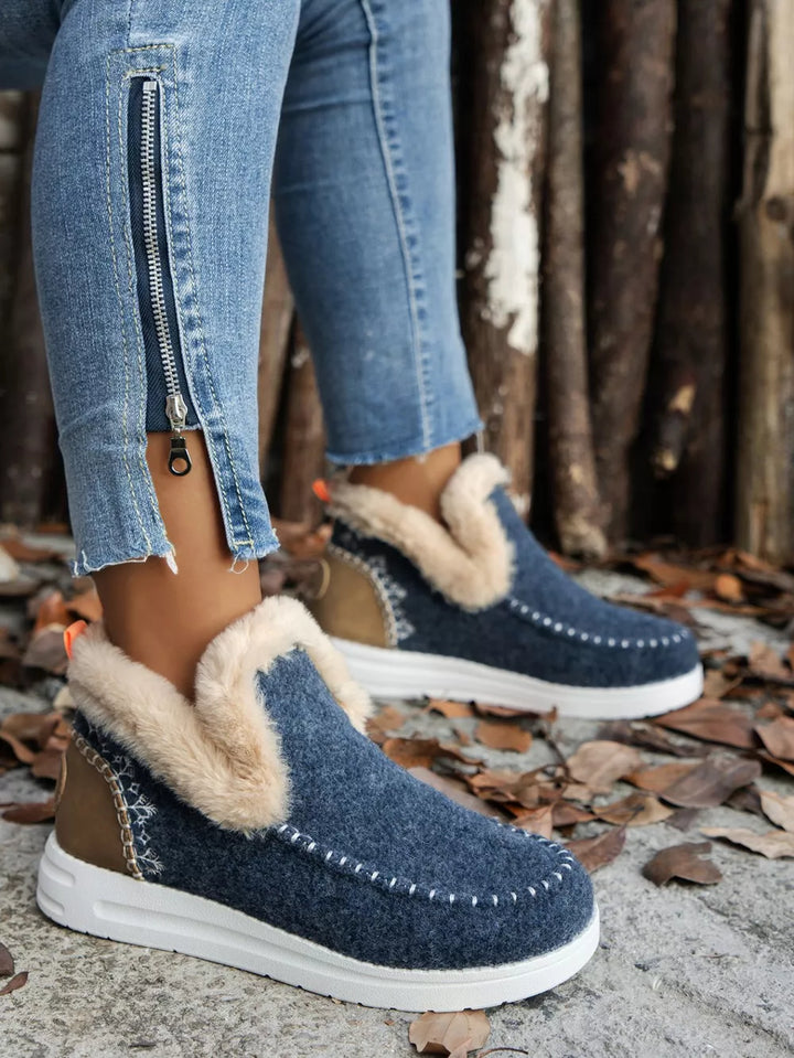 Navy studded ankle boot, side view on foot with a zip detail on the jeans