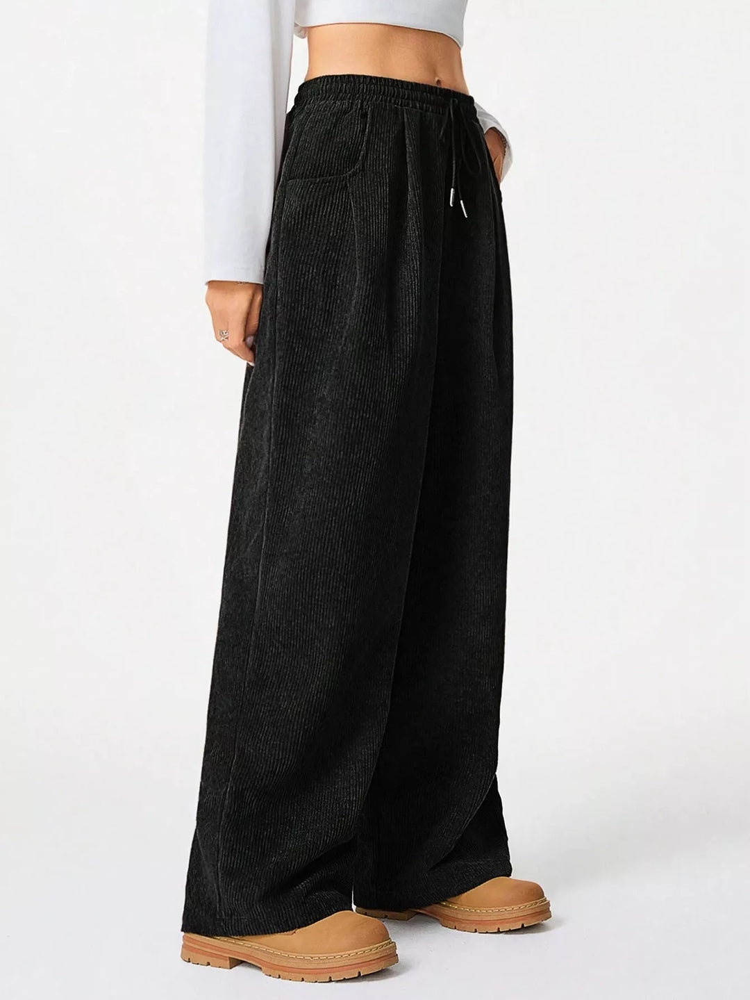 Front view of black baggy drawstring pants with tan boots