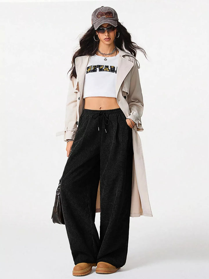 Black wide leg pants styled with a white crop top and long trench coat
