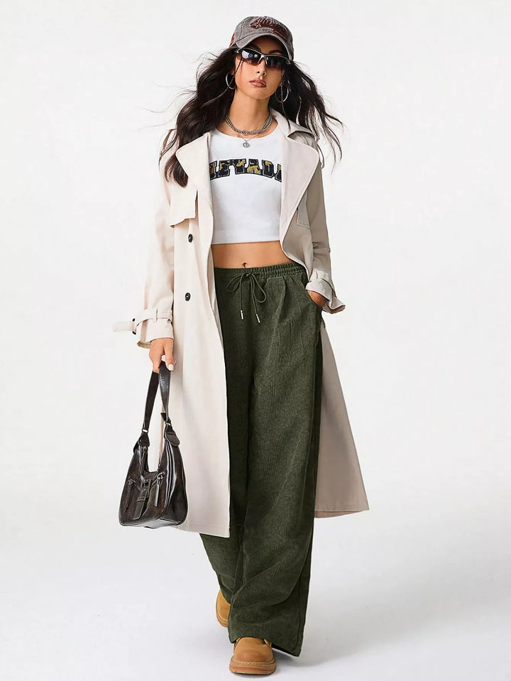 Olive baggy pants styled with a crop top, trench coat and handbag