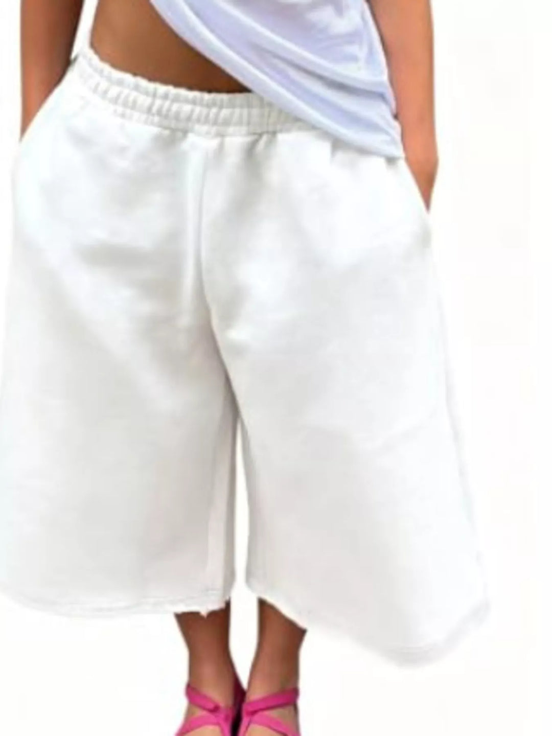 White baggy shorts with wide legs and a raw frayed hem, front view