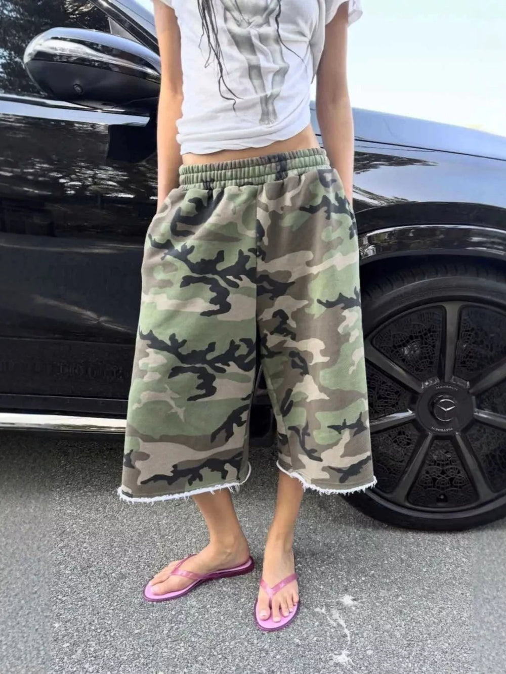 Woodland camo baggy shorts styled with a gray tee and pink flip flops