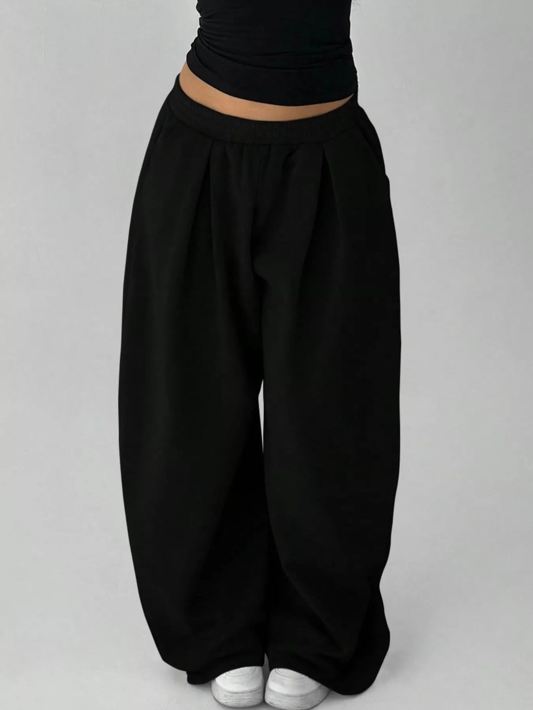 Black baggy sweatpants against a plain backdrop, front view