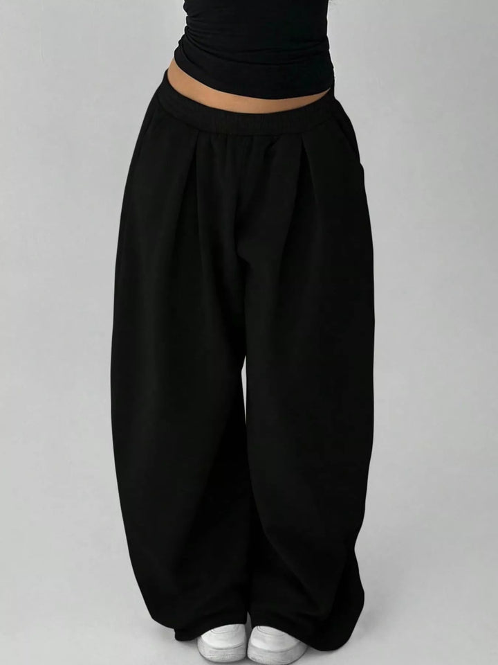 Black baggy sweatpants against a plain backdrop, front view