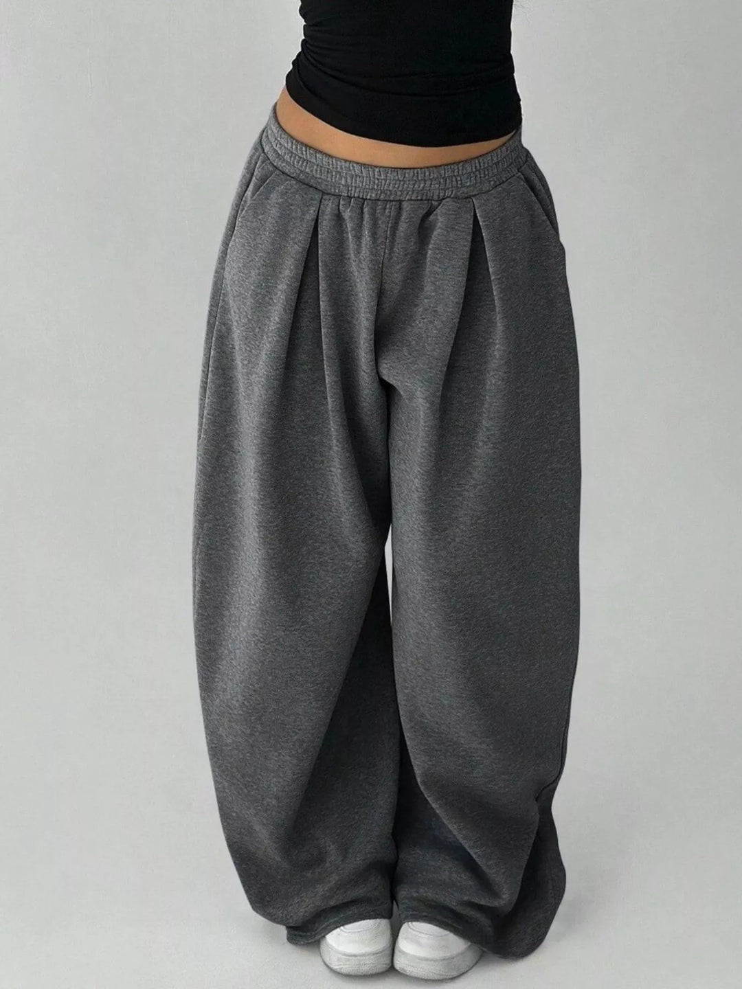 Charcoal baggy sweatpants on a plain backdrop, front view