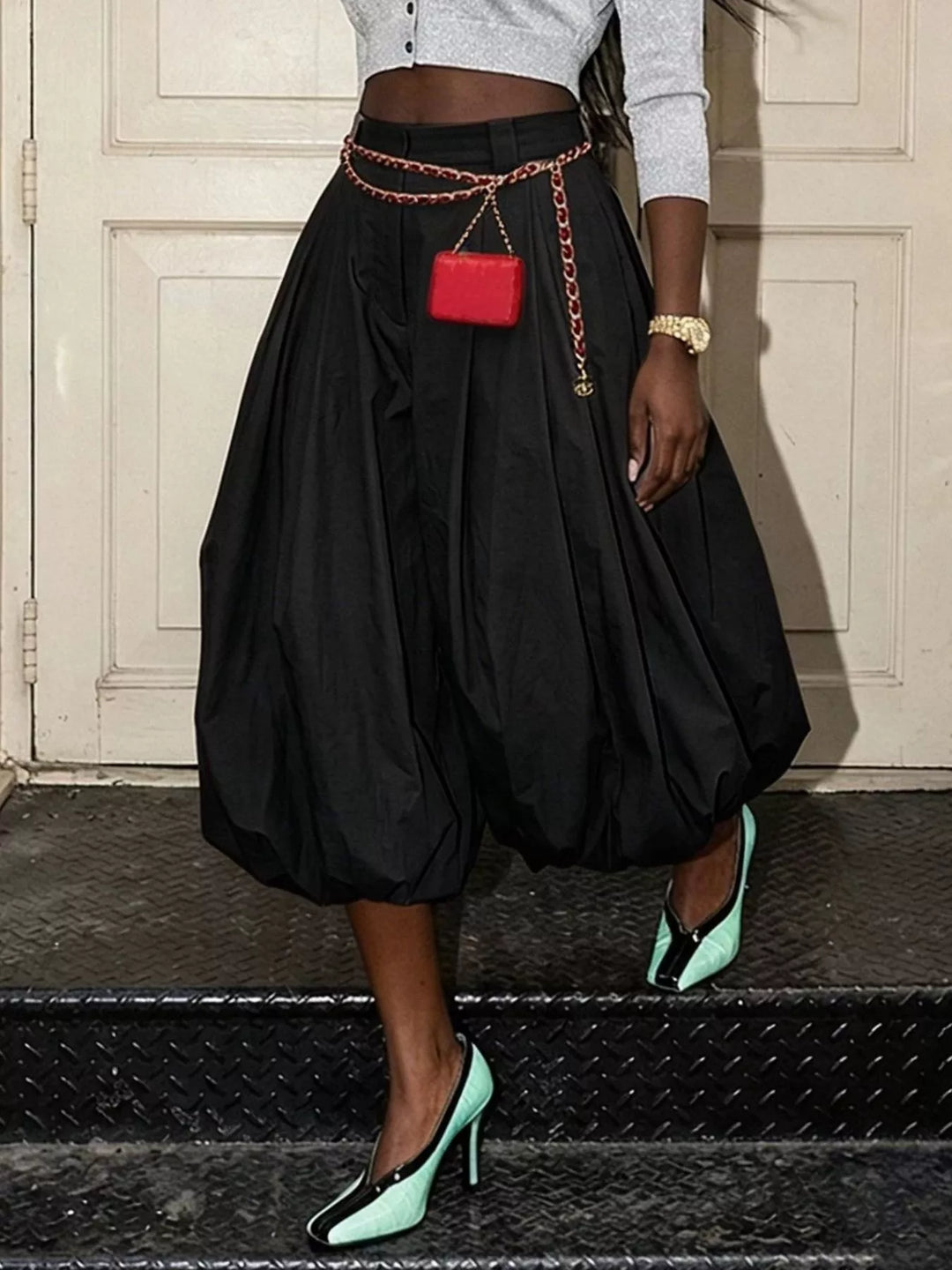 Black balloon pants with pleats, front view with a small red bag