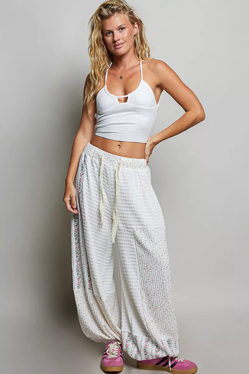 Ivory wide leg balloon pants worn with a white halter top, hand on hip