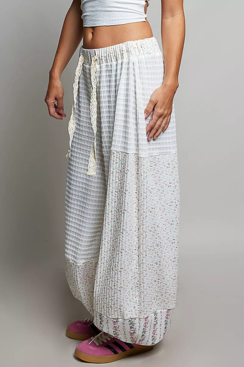 Ivory patchwork balloon pants seen from a slight angle with drawstring waist