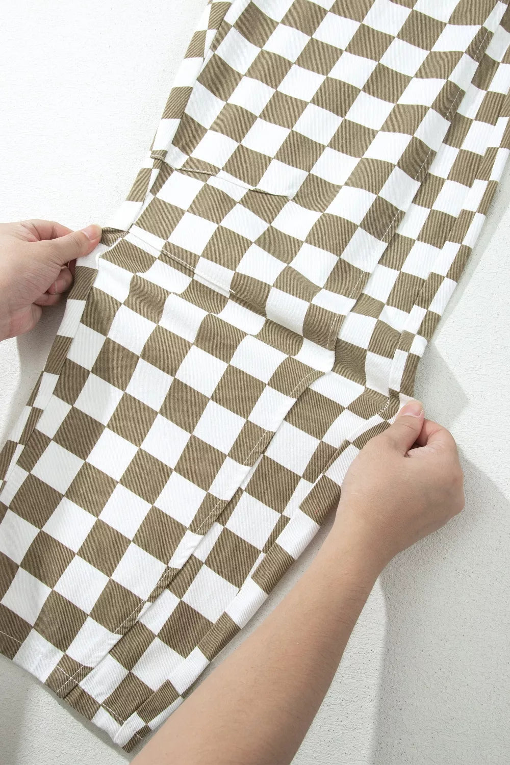 Hands showing the roomy barrel leg shape of the checkerboard pants