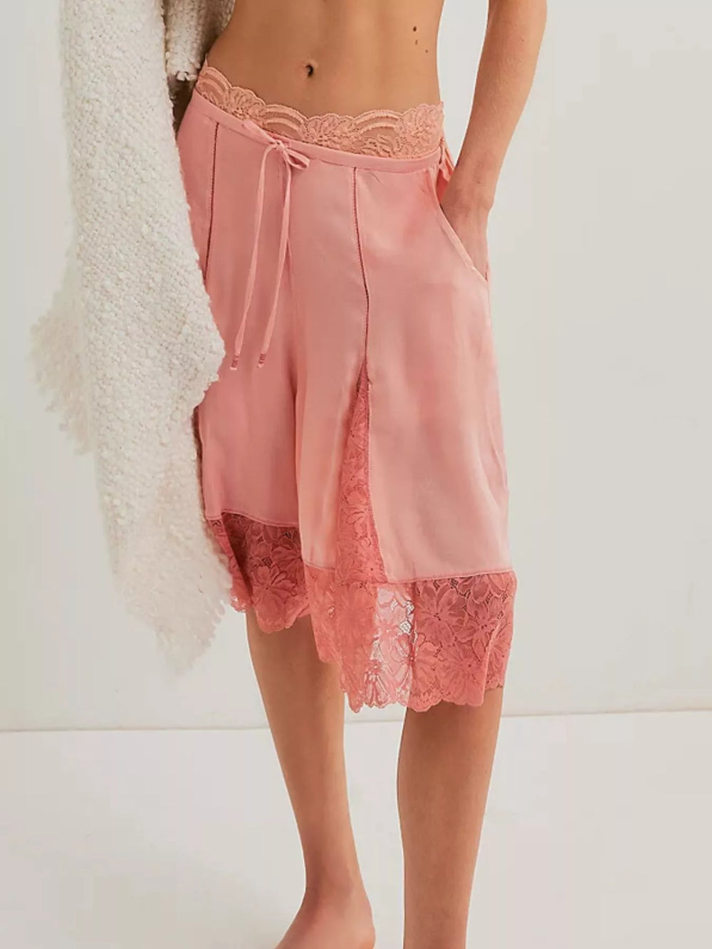 Pink satin-look Bermuda shorts with lace panels styled with a cream cami top
