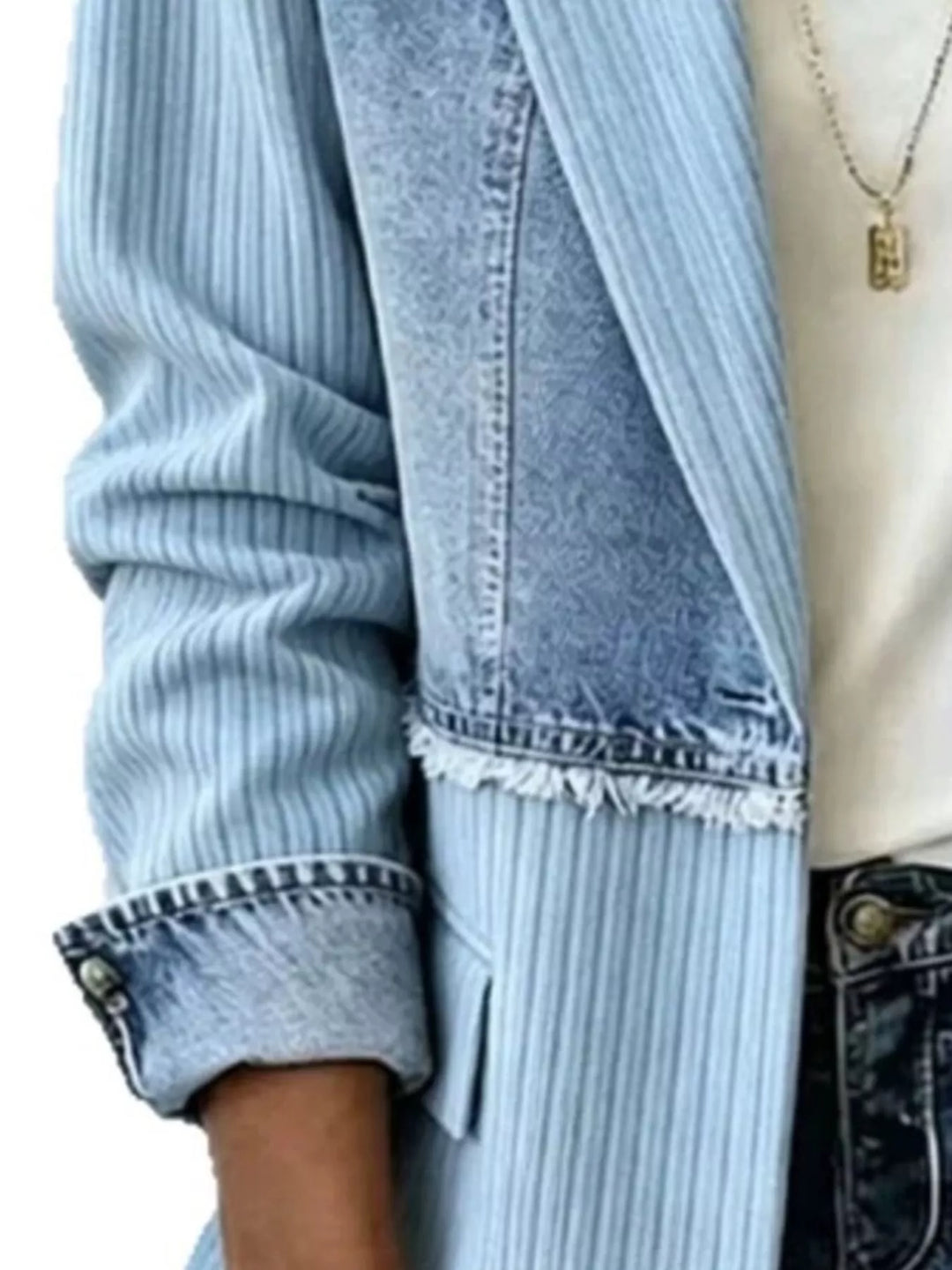 Close-up of light blue blazer jacket with frayed denim hem and rolled cuff