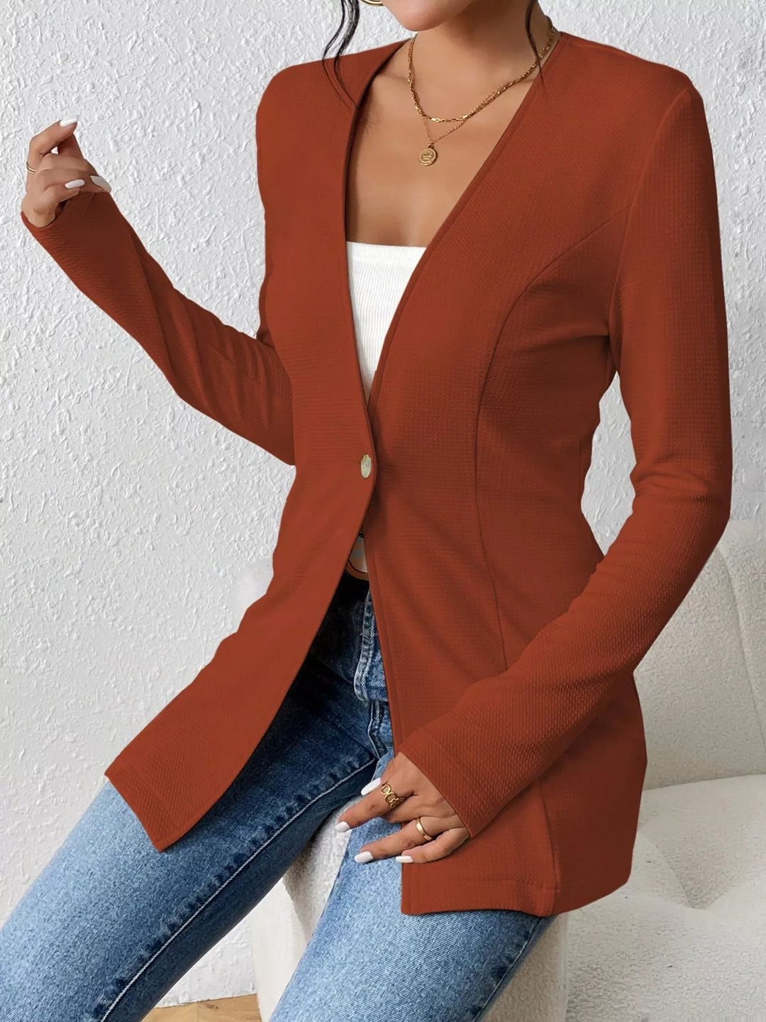 Rust one button blazer on-model with a hand raised, V neck front