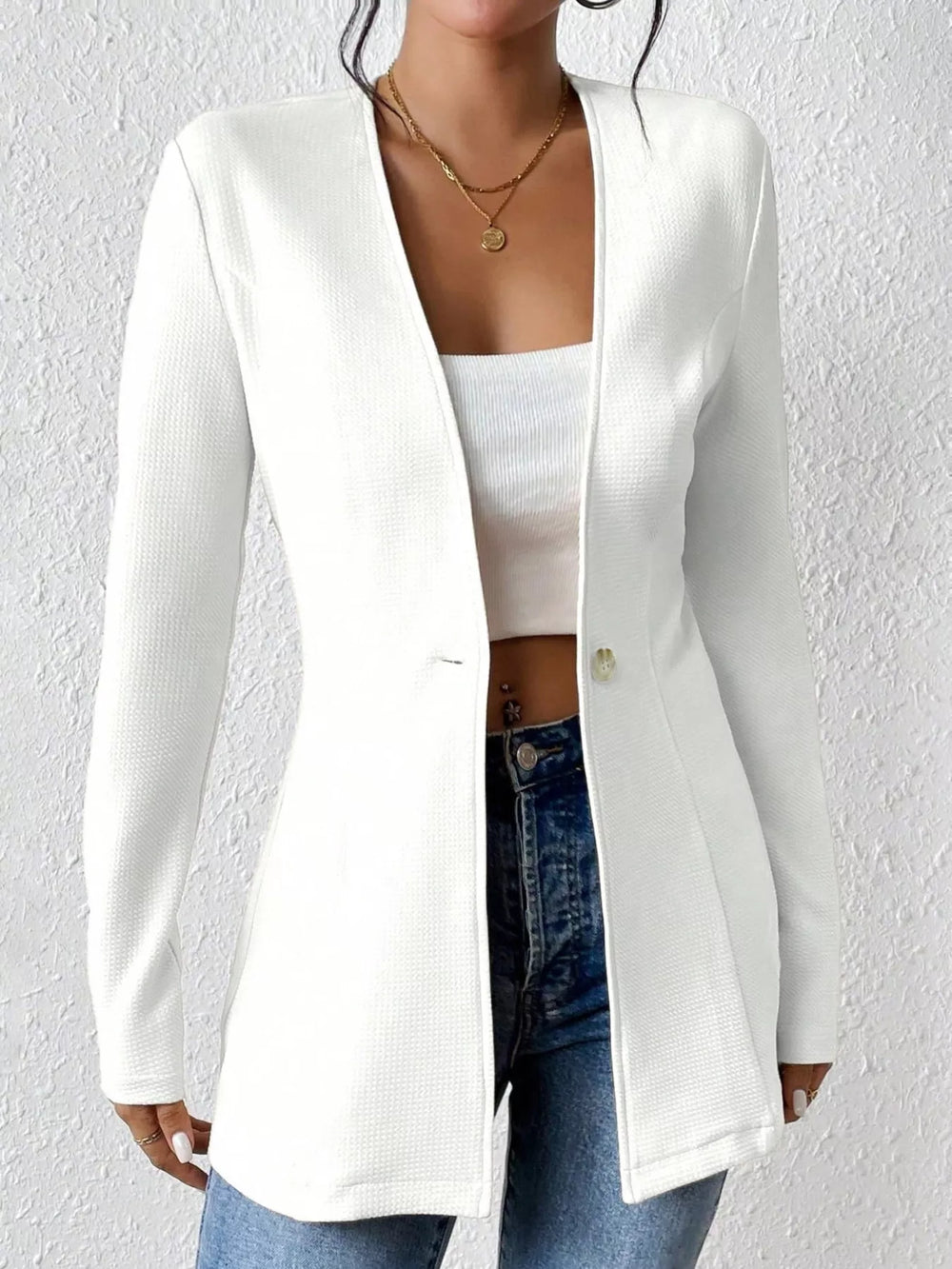 White collarless blazer worn open over a white top and jeans