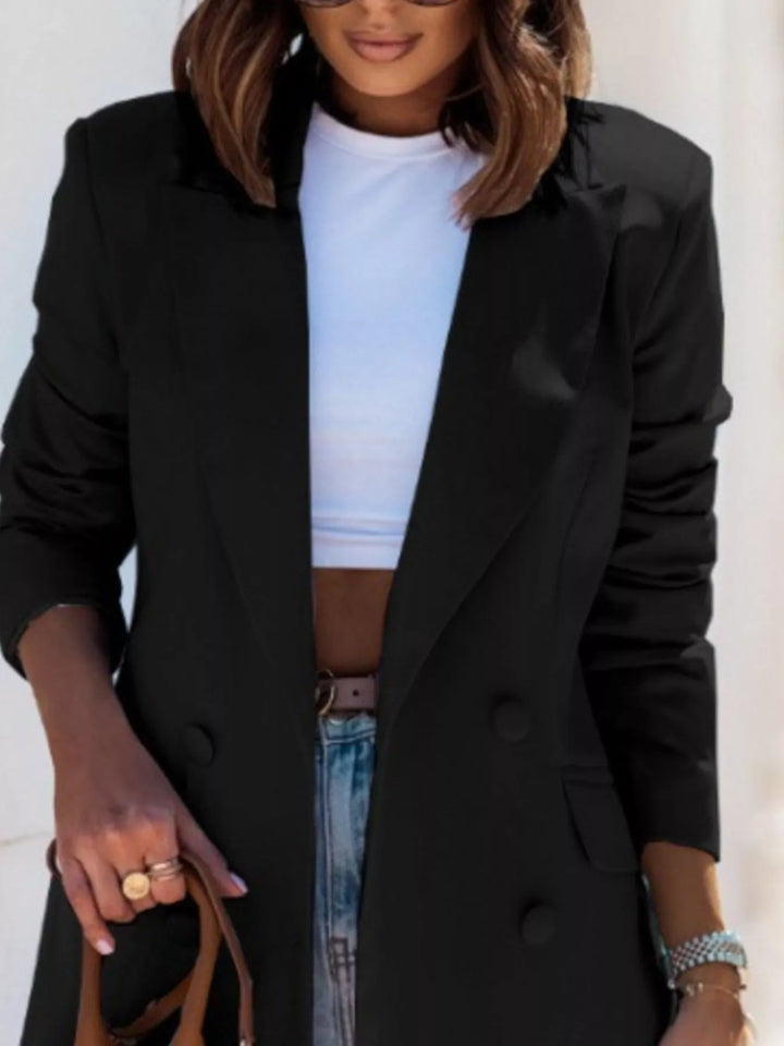Close-up of the black double breasted blazer with notch lapel over a white top