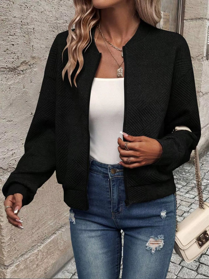 Black quilted diamond bomber jacket in a walking pose with jeans