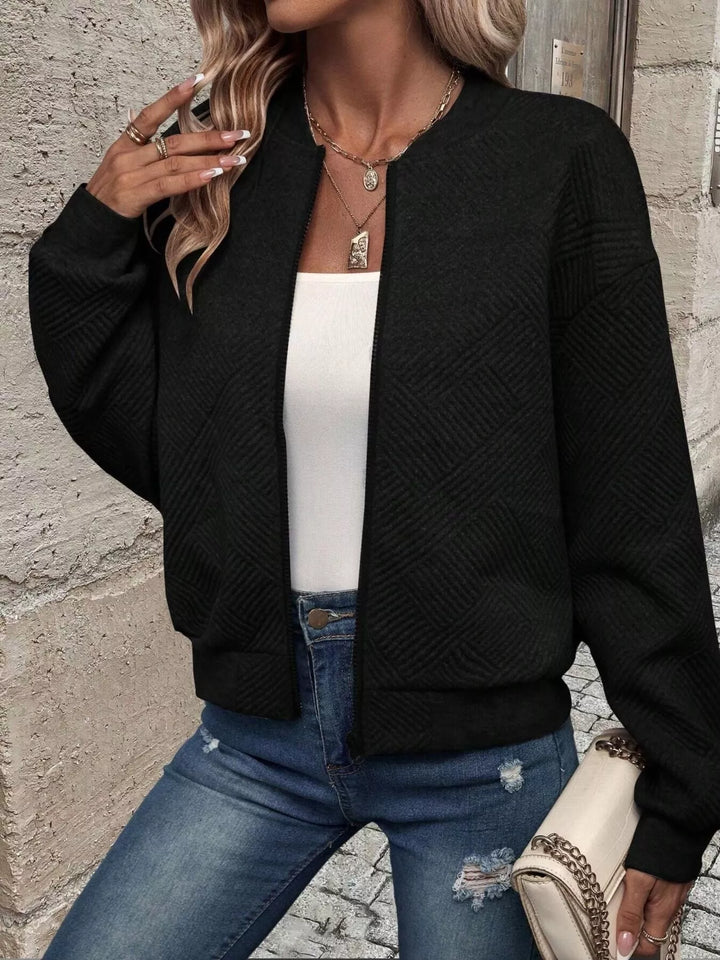Black cropped quilted bomber jacket worn open over a white top