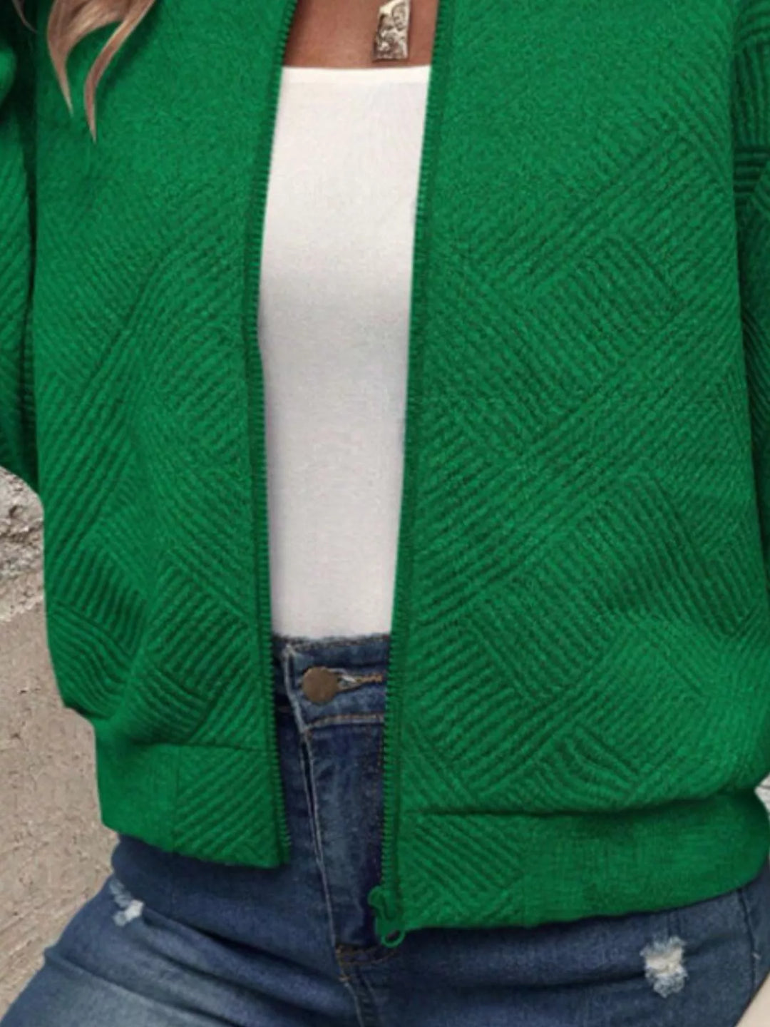 Close-up of the emerald green quilted diamond bomber jacket and ribbed hem