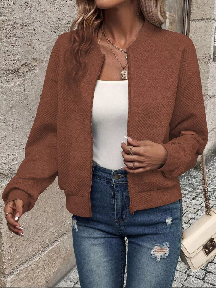 Rust brown cropped bomber jacket worn open in a walking pose