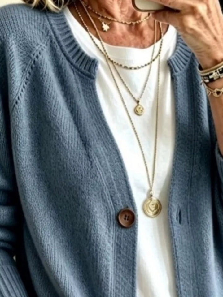 Close-up of the dusty blue cardigan crew neckline and wooden-look button