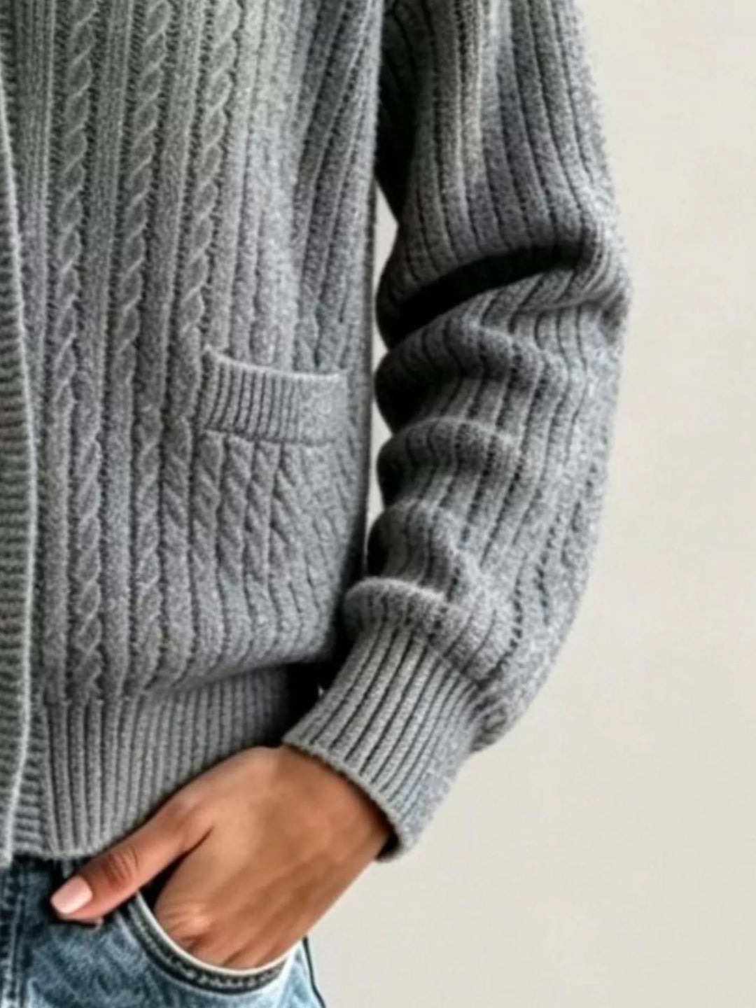 Charcoal cable knit cardigan side view showing patch pocket and ribbed cuff