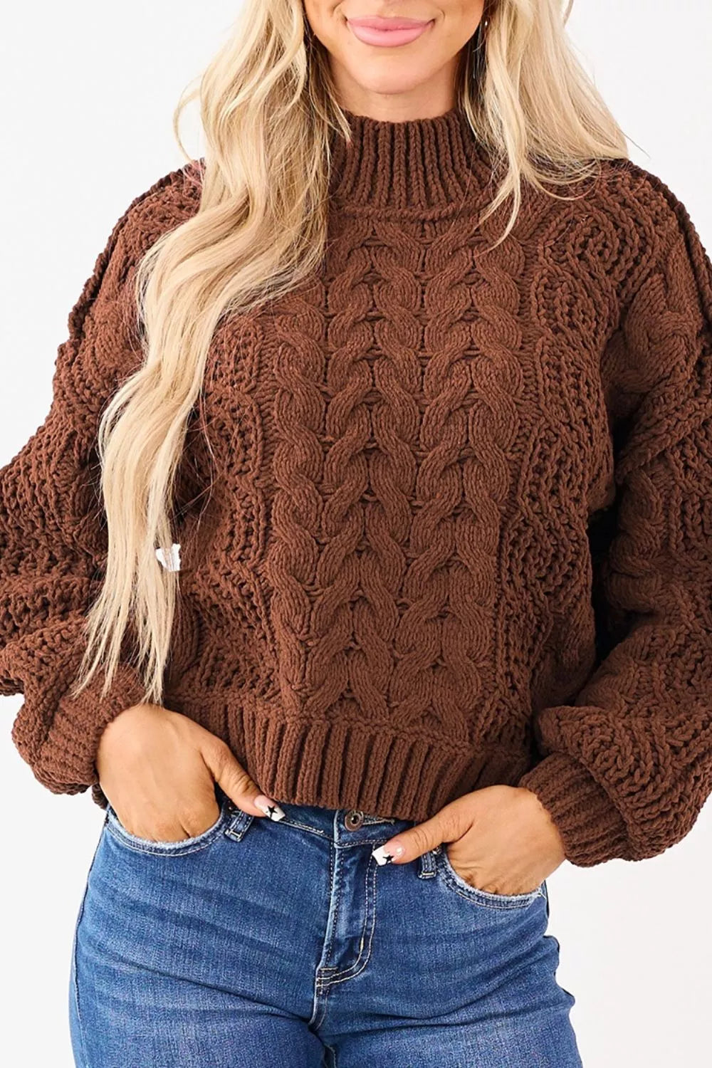 Chestnut mock neck cable knit sweater front view with hands in jeans pockets