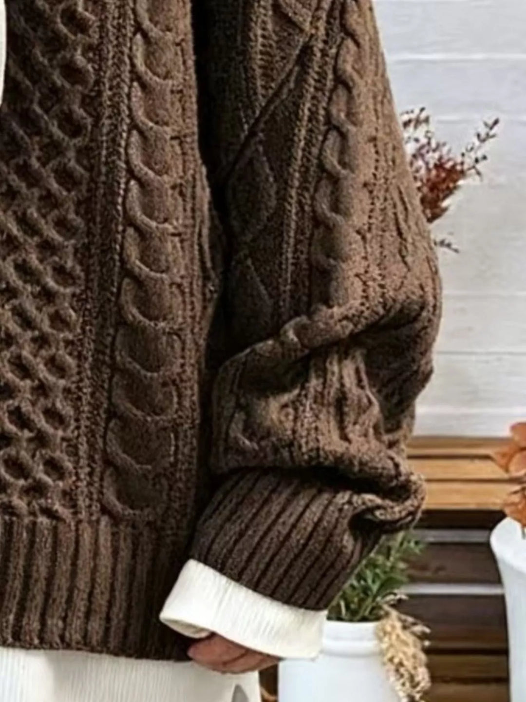 Close-up of the brown cable knit sleeve, ribbed cuff and side slit hem