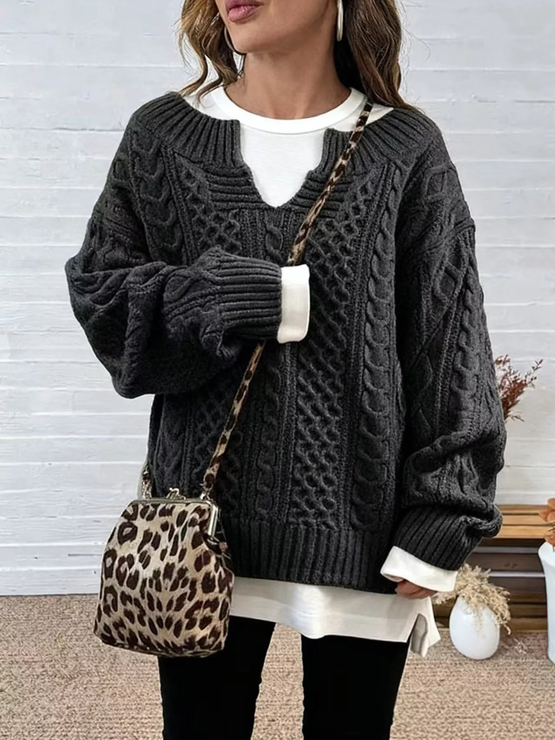 Front view of the charcoal cable knit sweater with a layered white hem