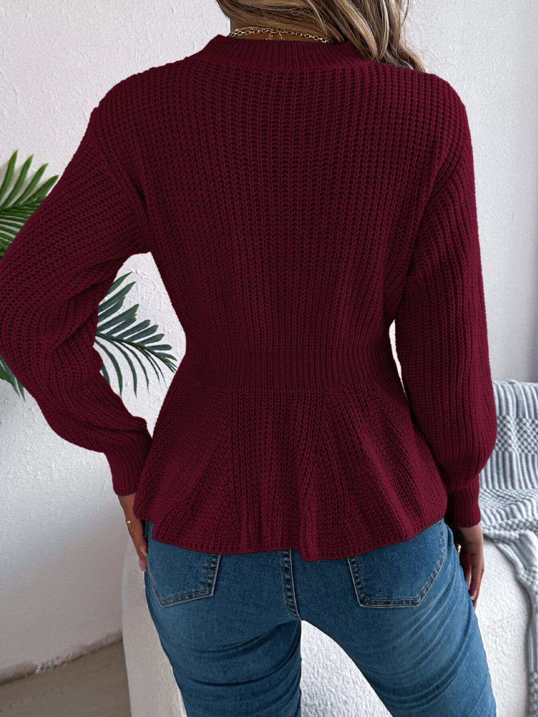Back view of the burgundy peplum hem sweater tucked at the waist