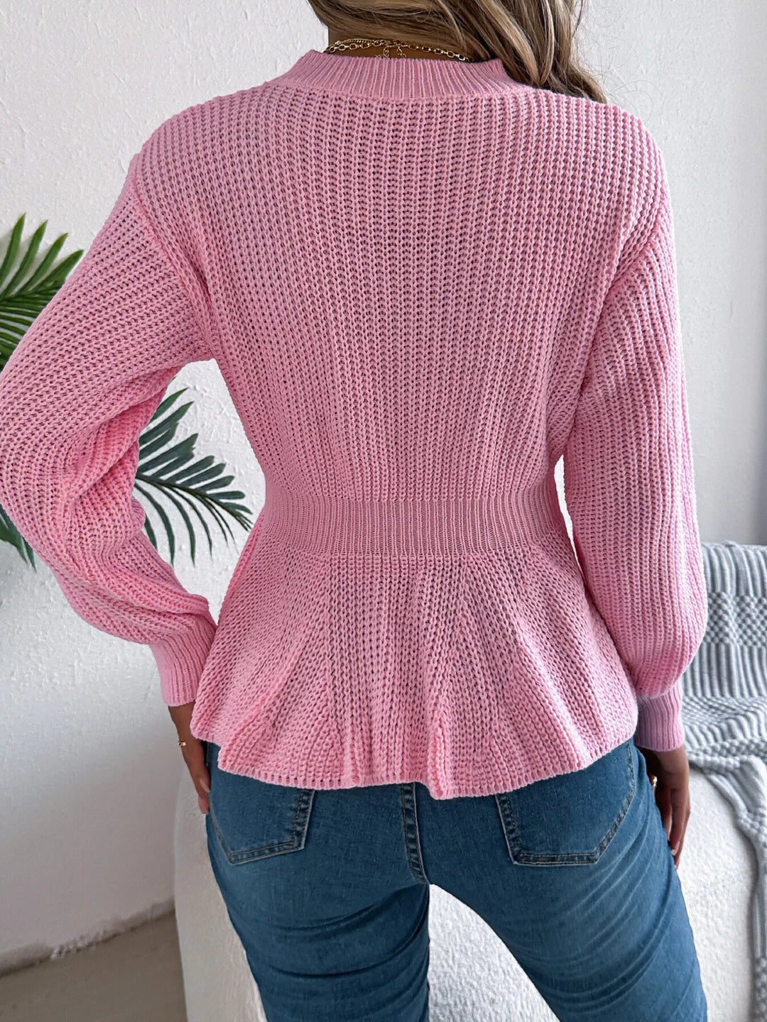 Back view of the pink peplum hem sweater with ribbed knit texture