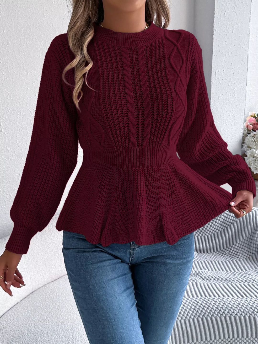 Burgundy peplum sweater with hand lifting the hem, full length